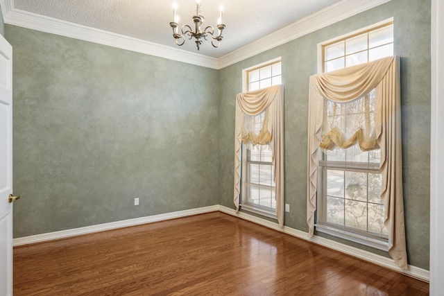 empty room featuring wood-type flooring, ornamental molding, and a notable chandelier