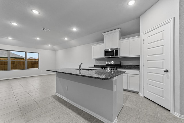 kitchen featuring sink, white cabinetry, dark stone countertops, appliances with stainless steel finishes, and a kitchen island with sink