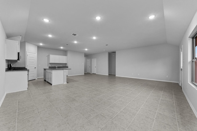 unfurnished living room with light tile patterned flooring, lofted ceiling, and sink