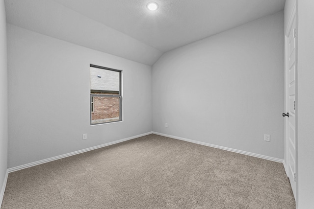 empty room with vaulted ceiling and carpet flooring