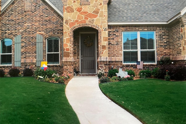 view of exterior entry featuring a lawn