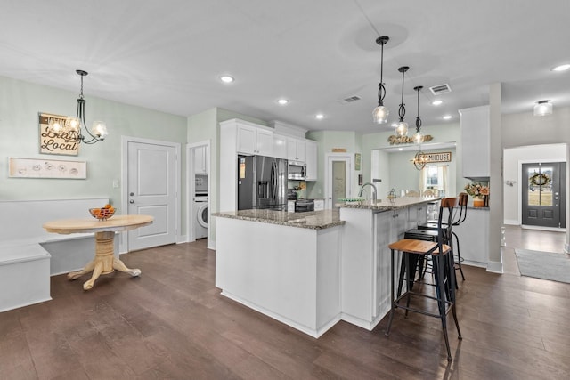 kitchen with a breakfast bar area, white cabinetry, decorative light fixtures, dark stone counters, and stainless steel appliances