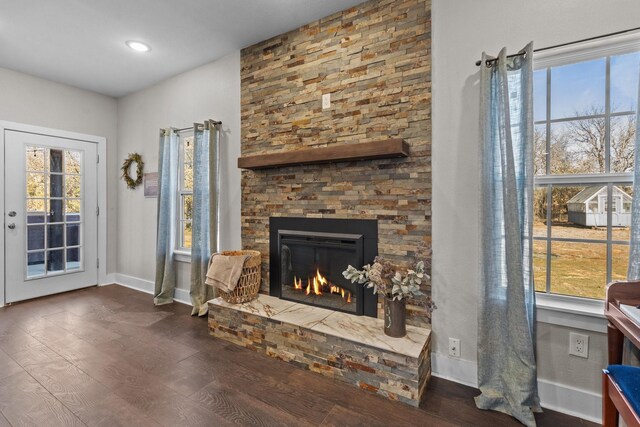 living room with dark wood-type flooring, ceiling fan, and a stone fireplace