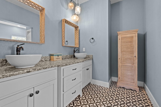 full bathroom with tile patterned floors, double vanity, baseboards, and a sink