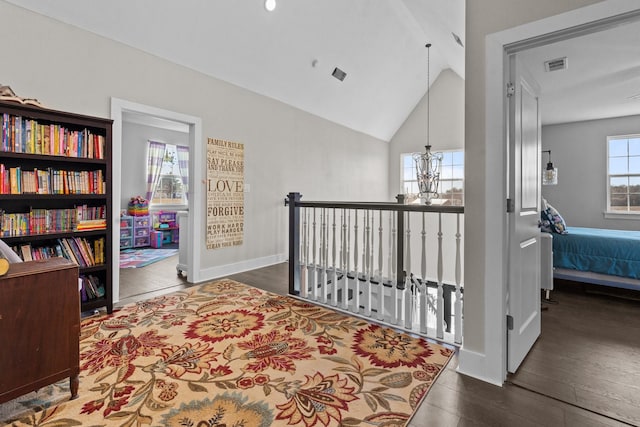 hall featuring baseboards, a notable chandelier, wood finished floors, and lofted ceiling