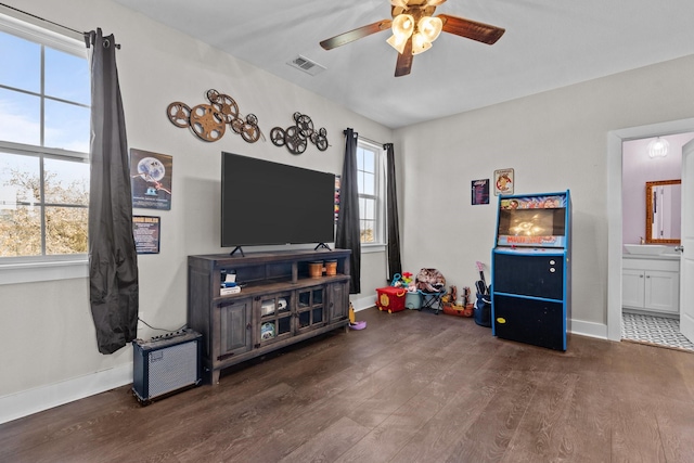 interior space featuring wood finished floors, ceiling fan, baseboards, and visible vents