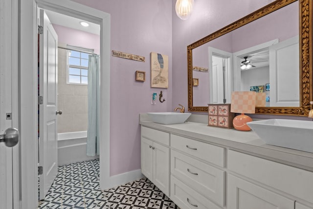 full bathroom with ceiling fan, double vanity, a sink, and baseboards