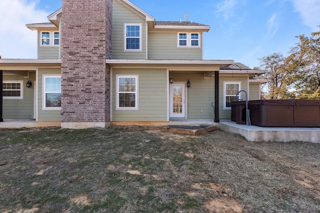 back of property featuring a yard, a patio, and a hot tub