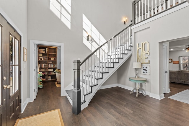 foyer entrance featuring baseboards, a high ceiling, a ceiling fan, stairway, and wood finished floors