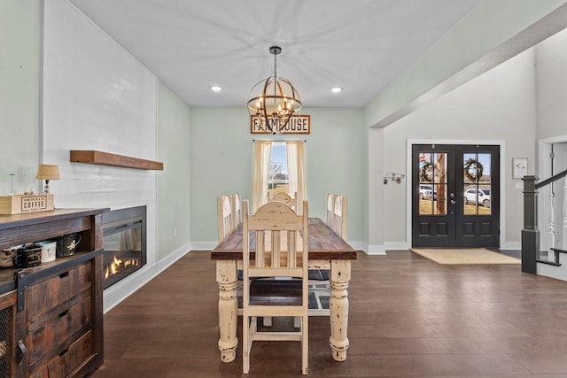 dining space with wood-type flooring, recessed lighting, an inviting chandelier, and a glass covered fireplace