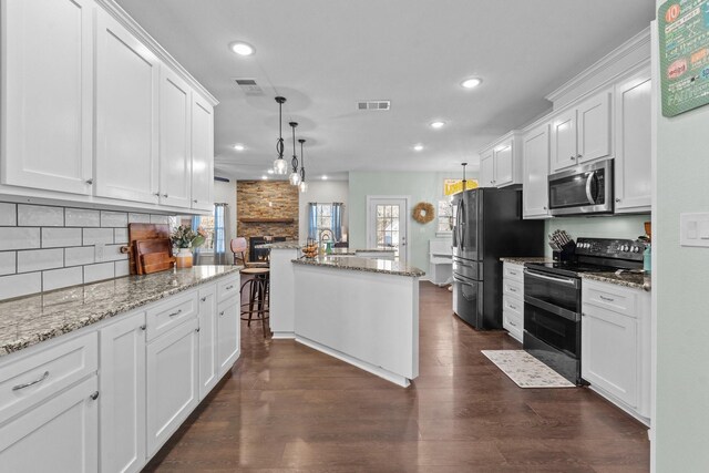 kitchen featuring white cabinetry, a kitchen island with sink, a kitchen breakfast bar, and appliances with stainless steel finishes