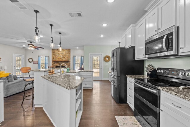 kitchen featuring sink, light stone counters, white cabinets, stainless steel fridge with ice dispenser, and decorative light fixtures