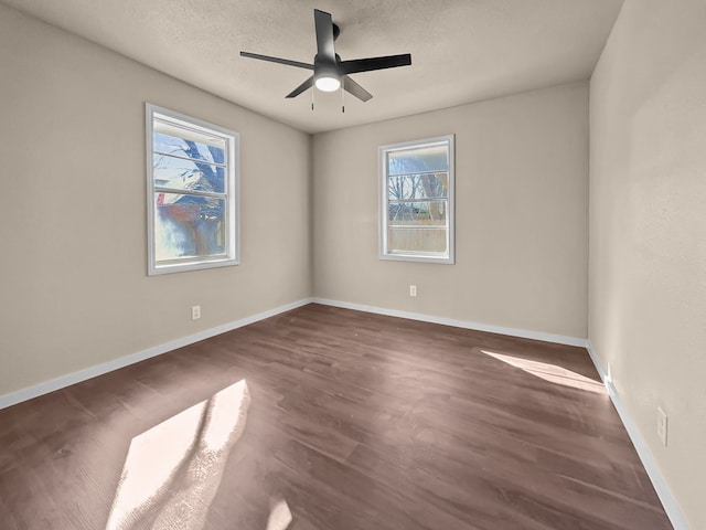 empty room featuring dark wood-type flooring, ceiling fan, and a textured ceiling