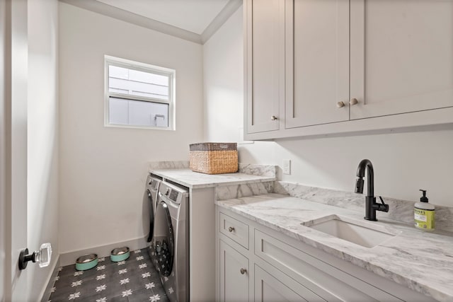 washroom with cabinet space, baseboards, a sink, and independent washer and dryer