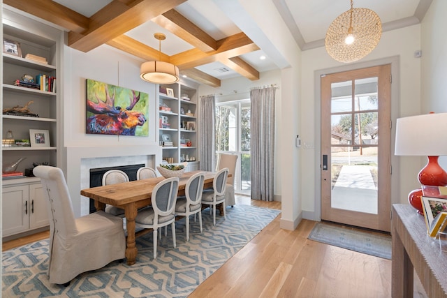 dining area with coffered ceiling, a fireplace, baseboards, light wood-style floors, and beam ceiling