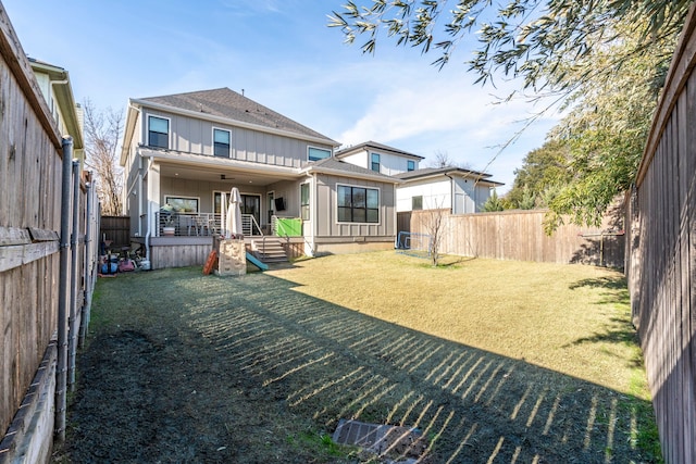 rear view of house with a fenced backyard, a lawn, and board and batten siding