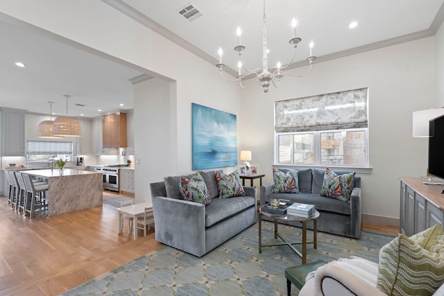 living area with light wood-style floors, visible vents, and crown molding