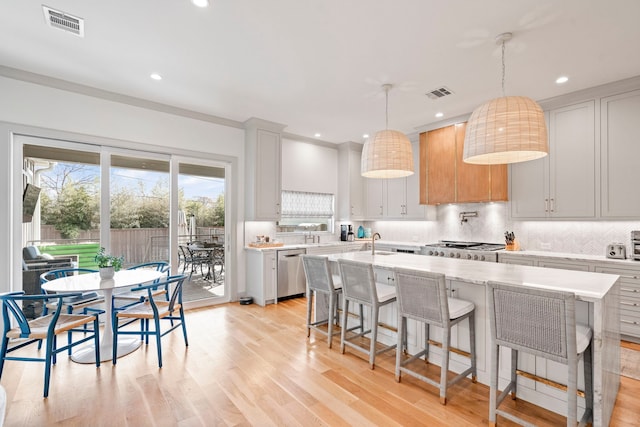 kitchen with an island with sink, a sink, pendant lighting, and stainless steel dishwasher