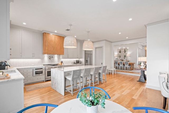 kitchen featuring light wood finished floors, a kitchen island, built in appliances, pendant lighting, and backsplash