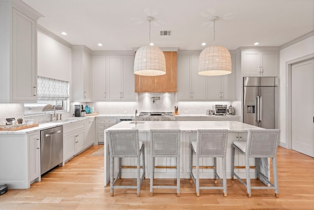 kitchen featuring appliances with stainless steel finishes, a kitchen island, white cabinetry, and pendant lighting