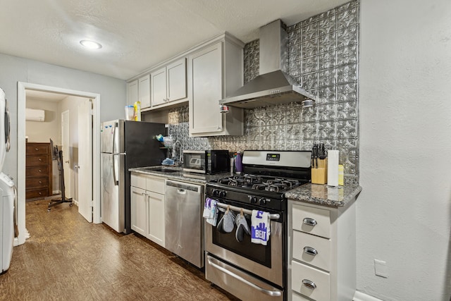 kitchen with appliances with stainless steel finishes, tasteful backsplash, white cabinetry, dark stone countertops, and wall chimney exhaust hood