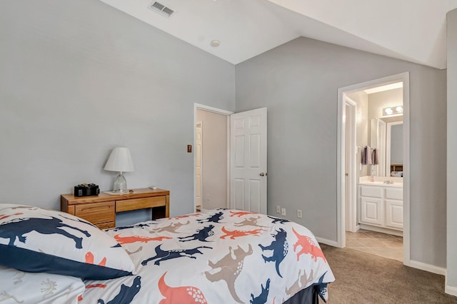 bedroom with connected bathroom, vaulted ceiling, and light carpet