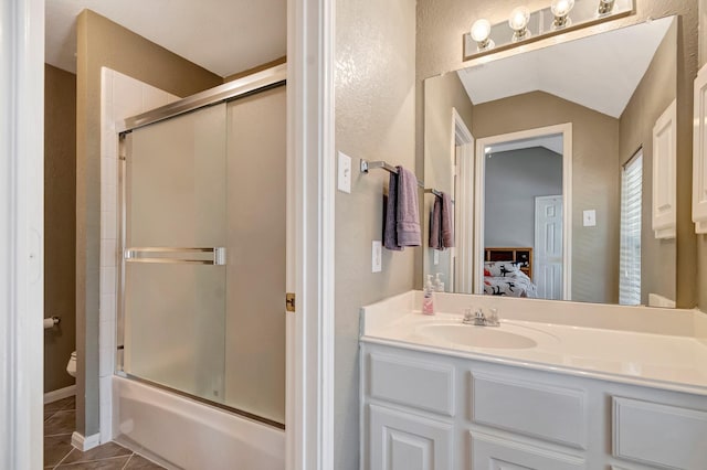 full bathroom featuring combined bath / shower with glass door, tile patterned flooring, vanity, vaulted ceiling, and toilet