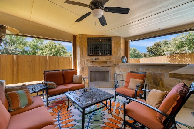 view of patio / terrace with ceiling fan and an outdoor living space with a fireplace