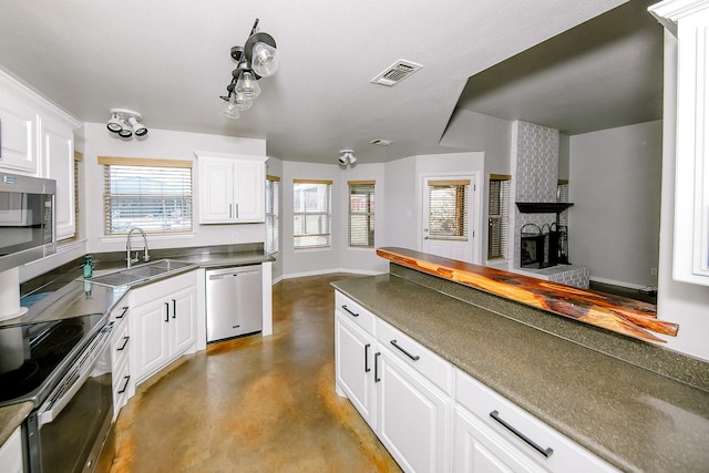 kitchen featuring sink, a brick fireplace, white cabinets, and appliances with stainless steel finishes