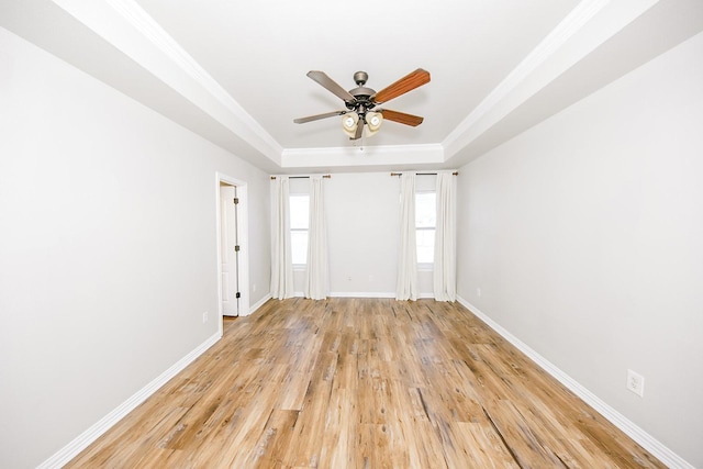 spare room with a raised ceiling, ornamental molding, ceiling fan, and light hardwood / wood-style floors