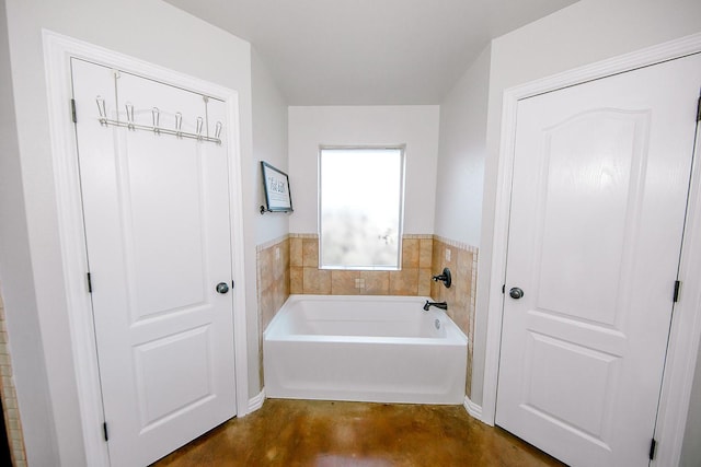 bathroom with concrete flooring and a bathing tub