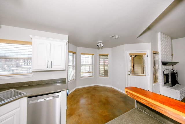 kitchen featuring stainless steel dishwasher, white cabinets, and a fireplace