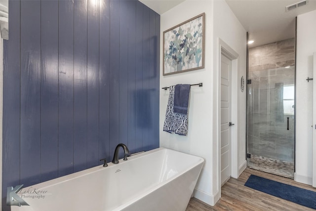 bathroom with independent shower and bath and hardwood / wood-style floors