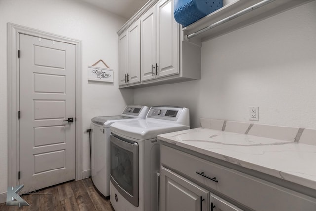 clothes washing area featuring dark hardwood / wood-style flooring, washing machine and dryer, and cabinets