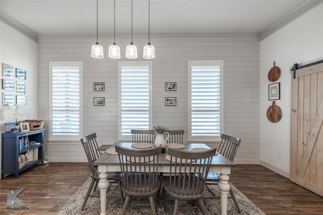 dining space with dark wood-type flooring, ornamental molding, and a barn door