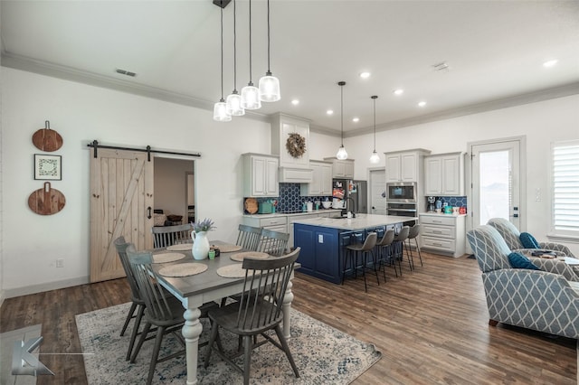 dining space featuring crown molding, sink, a barn door, and dark wood-type flooring