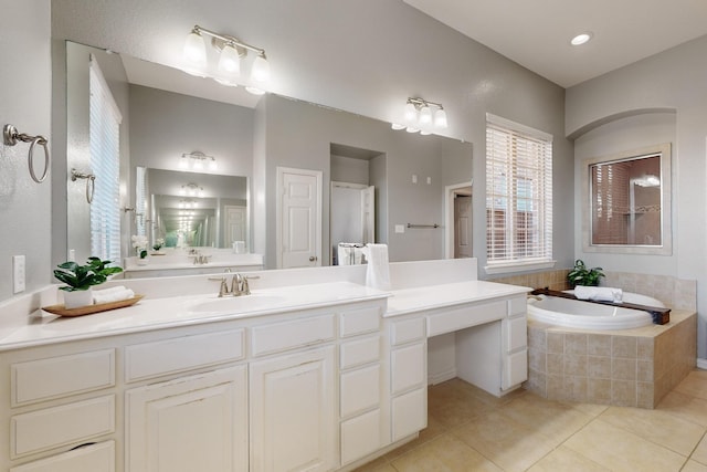 bathroom featuring tile patterned flooring, vanity, and tiled bath