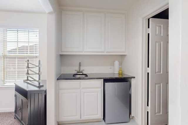 bar with stainless steel refrigerator, sink, and white cabinets