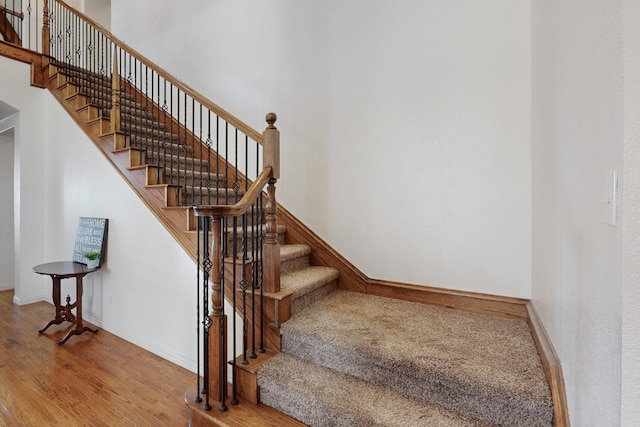 stairs with a towering ceiling and wood-type flooring