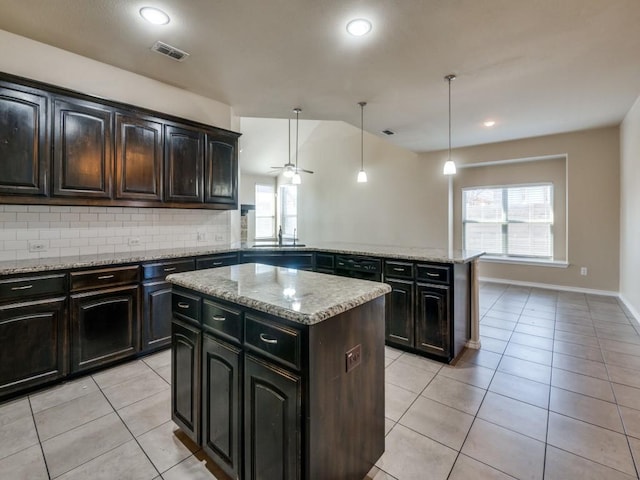 kitchen with a center island, light tile patterned floors, decorative backsplash, a ceiling fan, and a sink