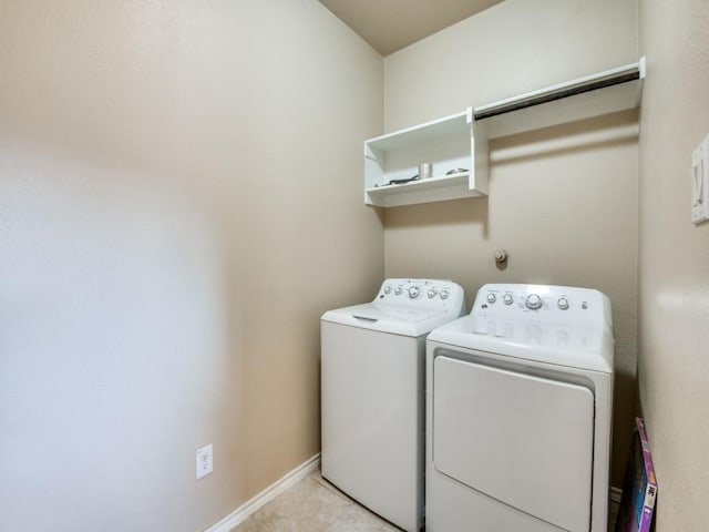 washroom with laundry area, light tile patterned floors, baseboards, and washer and clothes dryer