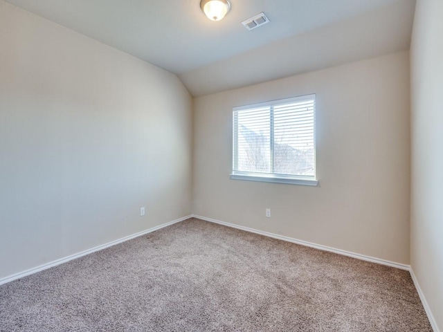 unfurnished room with carpet, visible vents, vaulted ceiling, and baseboards