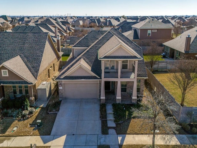 view of front of property featuring fence, a balcony, a garage, a residential view, and driveway