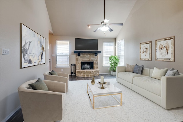 living room with baseboards, ceiling fan, wood finished floors, a fireplace, and high vaulted ceiling