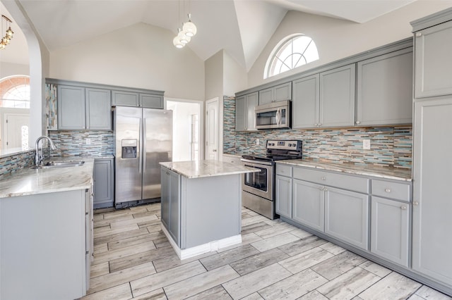 kitchen with pendant lighting, sink, gray cabinetry, a center island, and stainless steel appliances