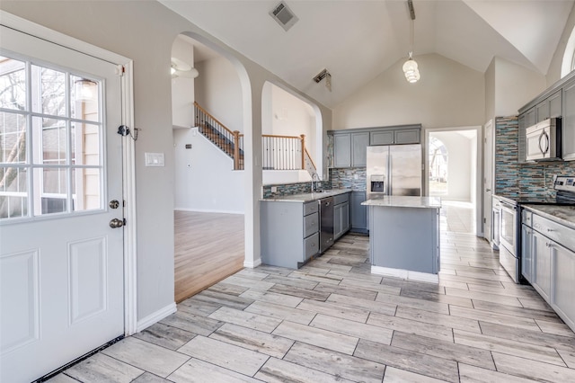 kitchen featuring hanging light fixtures, gray cabinets, stainless steel appliances, and a kitchen island