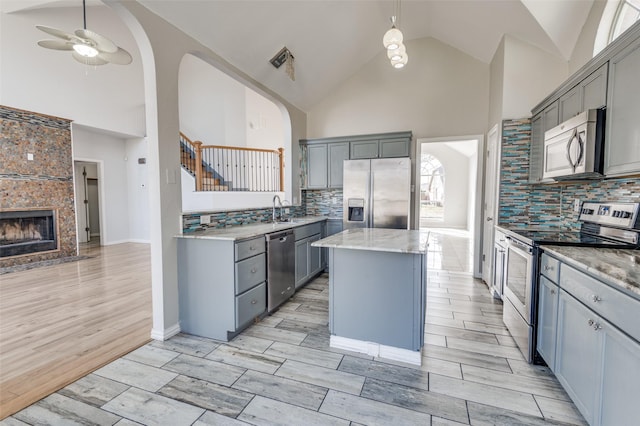 kitchen with sink, gray cabinetry, a center island, appliances with stainless steel finishes, and pendant lighting