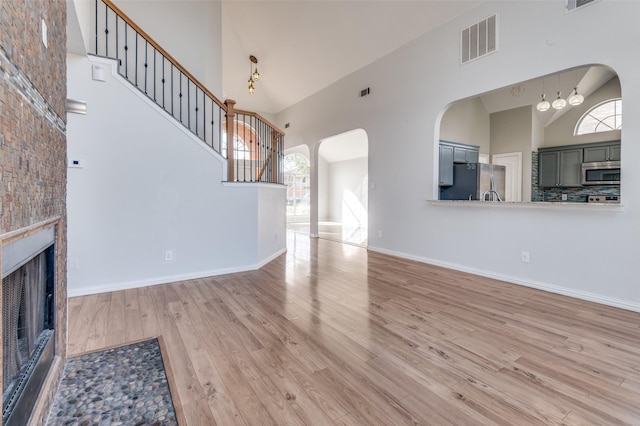 unfurnished living room featuring a towering ceiling and light wood-type flooring