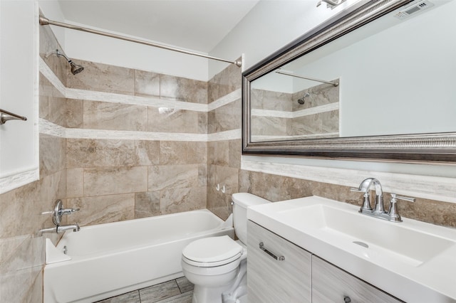 full bathroom featuring tile walls, vanity, toilet, and tiled shower / bath