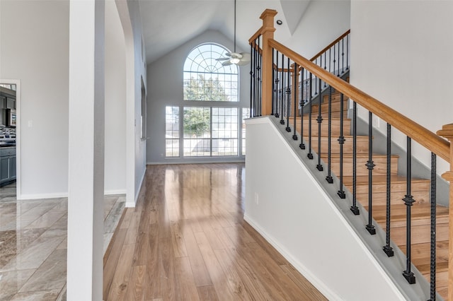 staircase with wood-type flooring and high vaulted ceiling